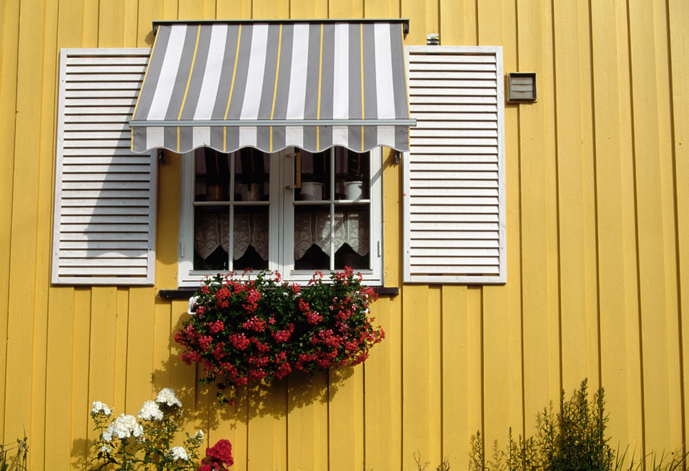 An awning over the window of a yellow house