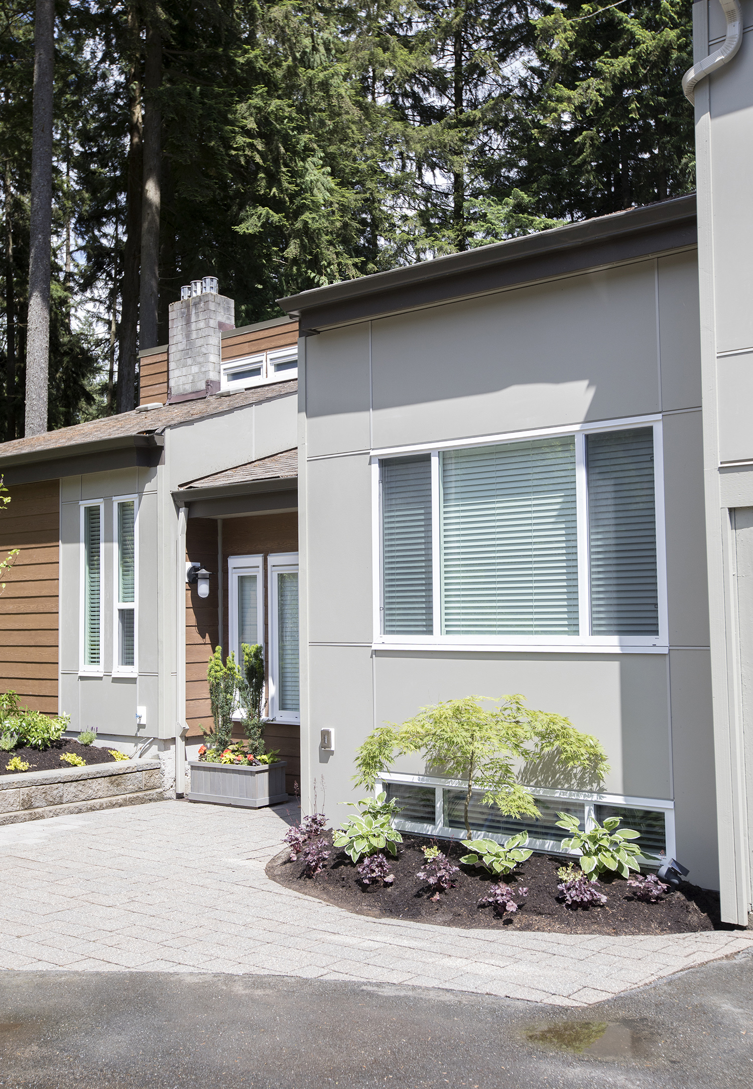 By using alternating flat-paneled and wood-grain siding on different “blocks” of this B.C. home, there is a strong textural change to the facade of this tree-ringed home, giving it a definitively modern vibe.