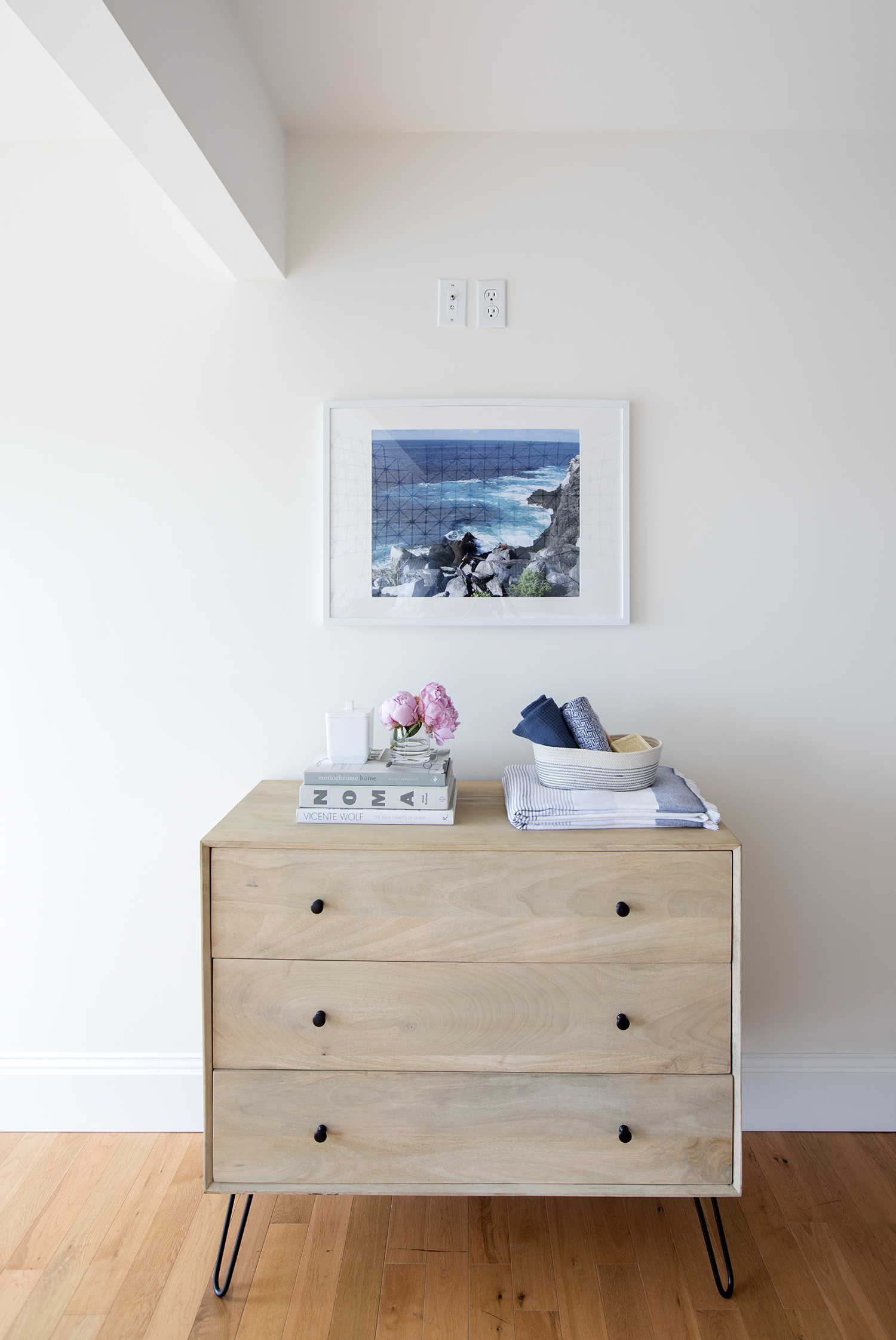 A rustic dresser with hairpin legs provides clothing storage as well as a surface to display artwork.