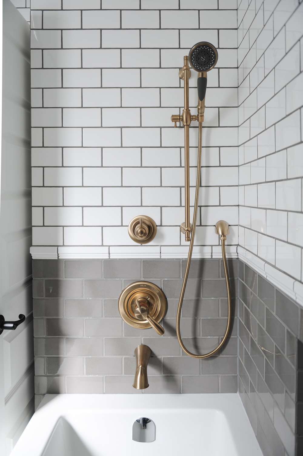 Exposed brass piping in a grey-tiled bathroom