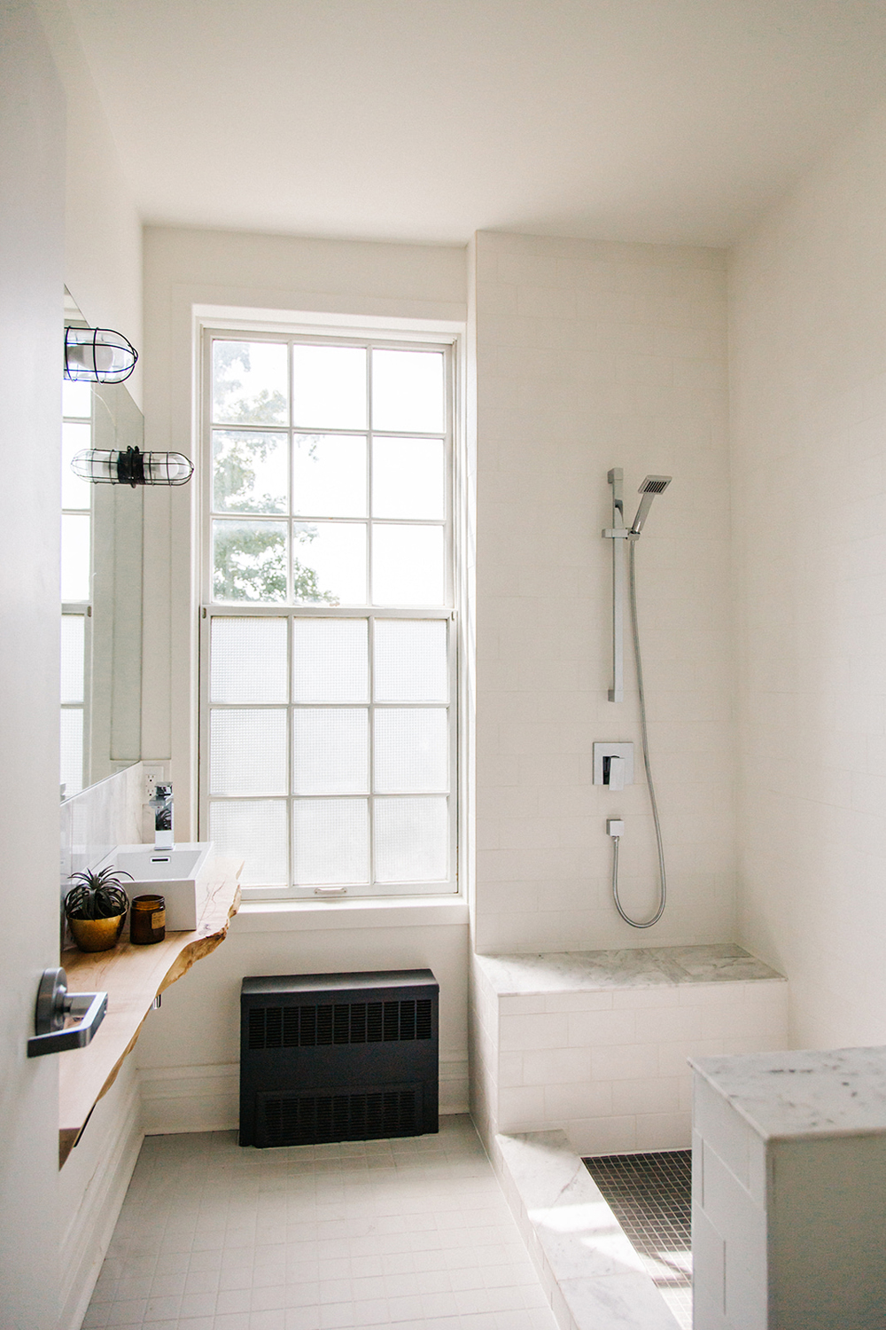 Off-white bathroom with open-concept standing shower featuring exposed pipes
