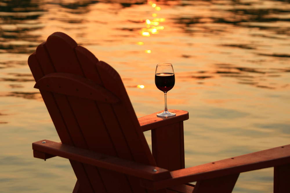 Chair and glass of wine on a dock at sunset