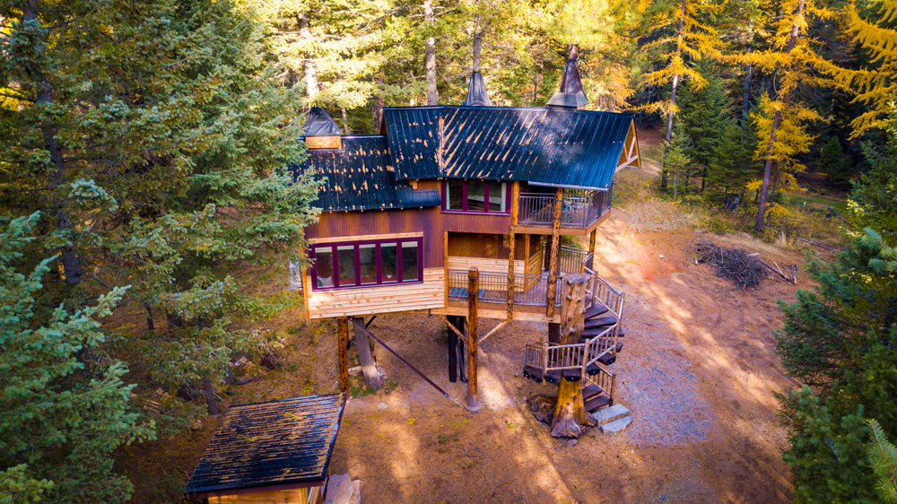 Cabin on stilts with spiral staircase and surrounded by trees