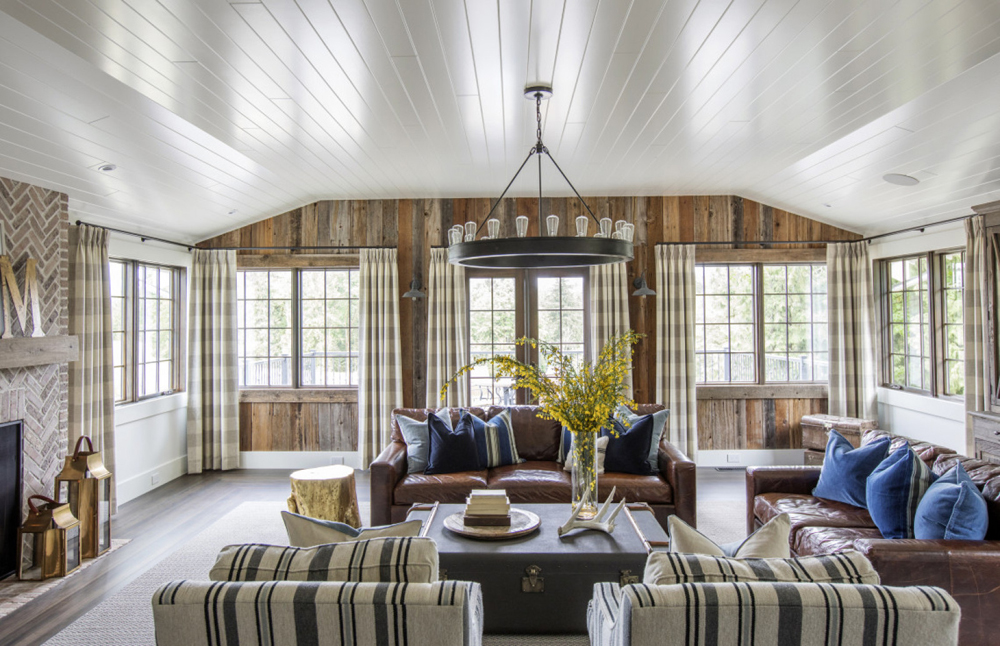 A renovated living room in a converted farmhouse with wood wall paneling and plaid furniture