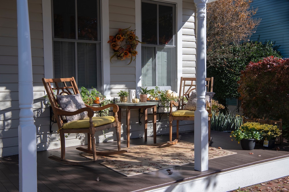 front porch with two rocking chairs and a table and ledges with mini pumpkins on top