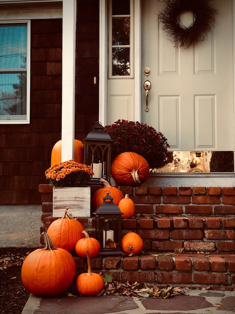 front porch and stairs decorated with pumpkins and lanterns