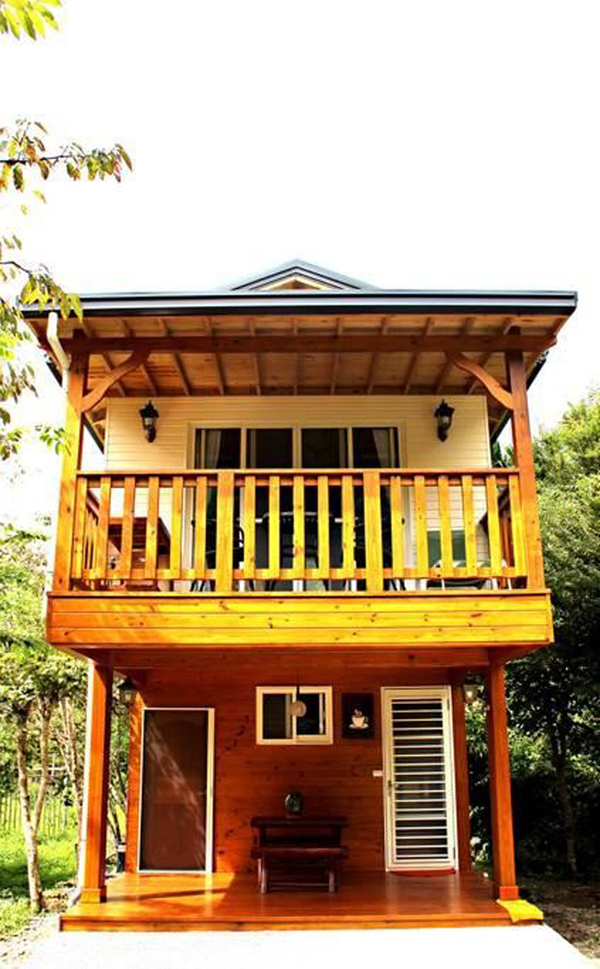 Narrow, rustic two-storey wood cabin with large balcony on second level