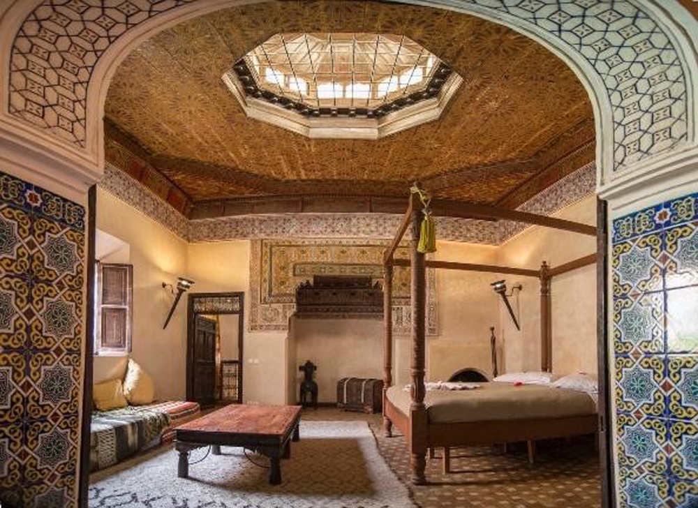 Main bedroom with circular dome roof and skylight, surrounded by wood furniture, patterned walls and carpeted floors