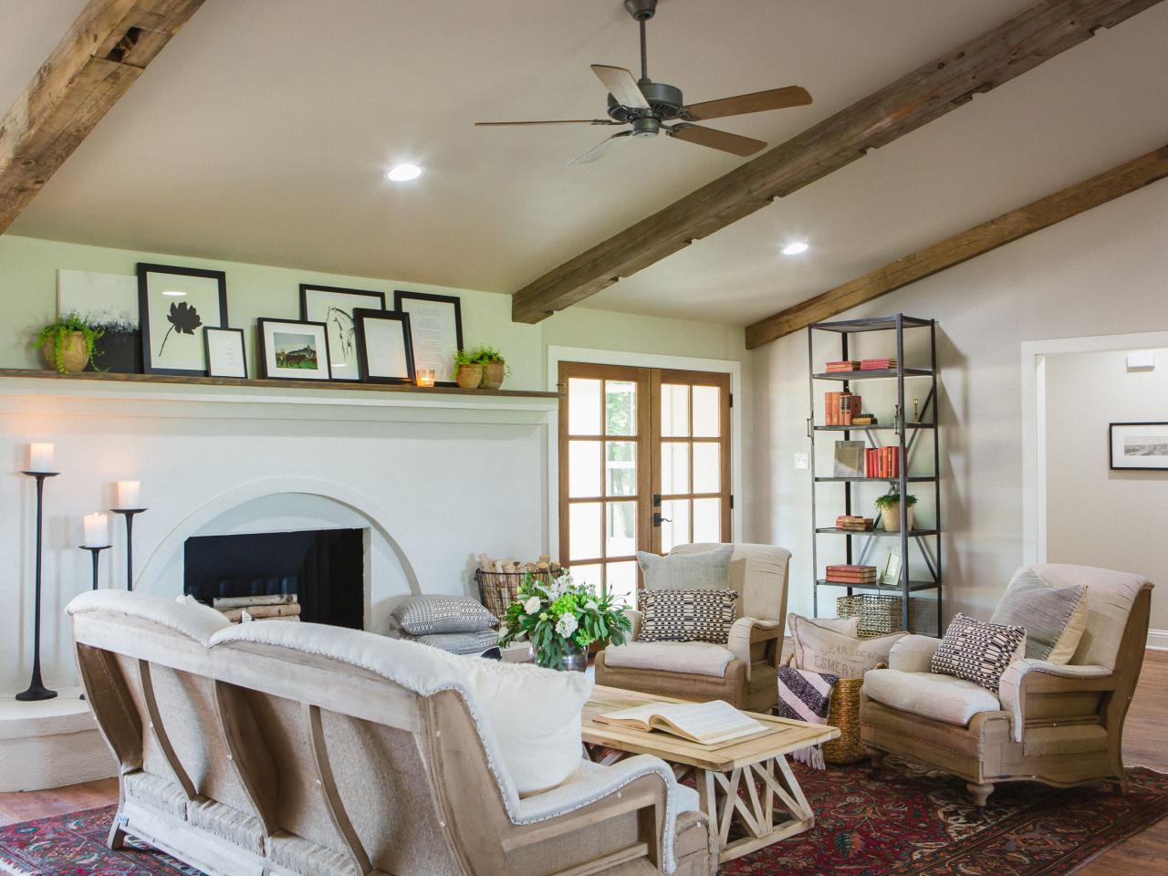 Living room fireplace that stretches along one wall with mantel adorned with picture frames and potted plants.