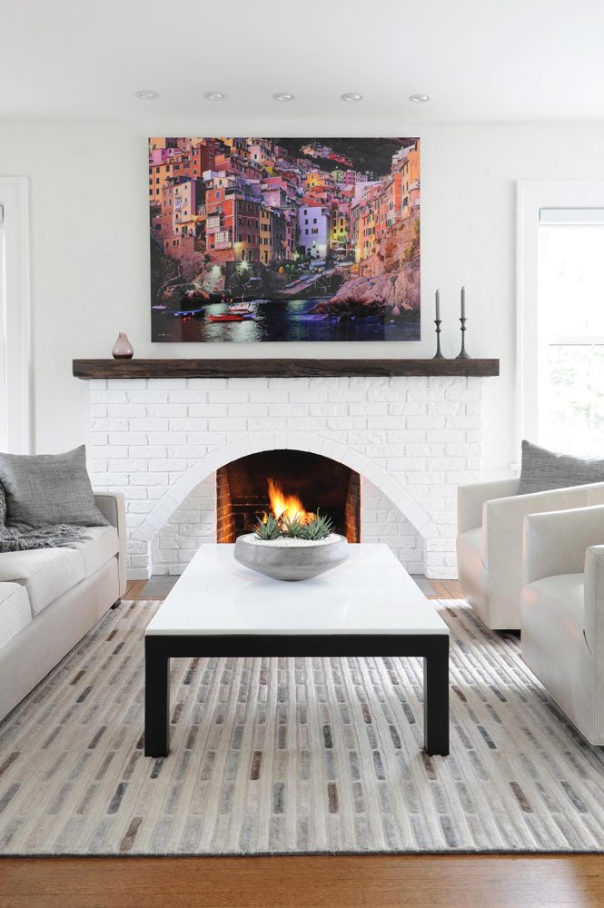 minimal white living room with colourful painting above mantel