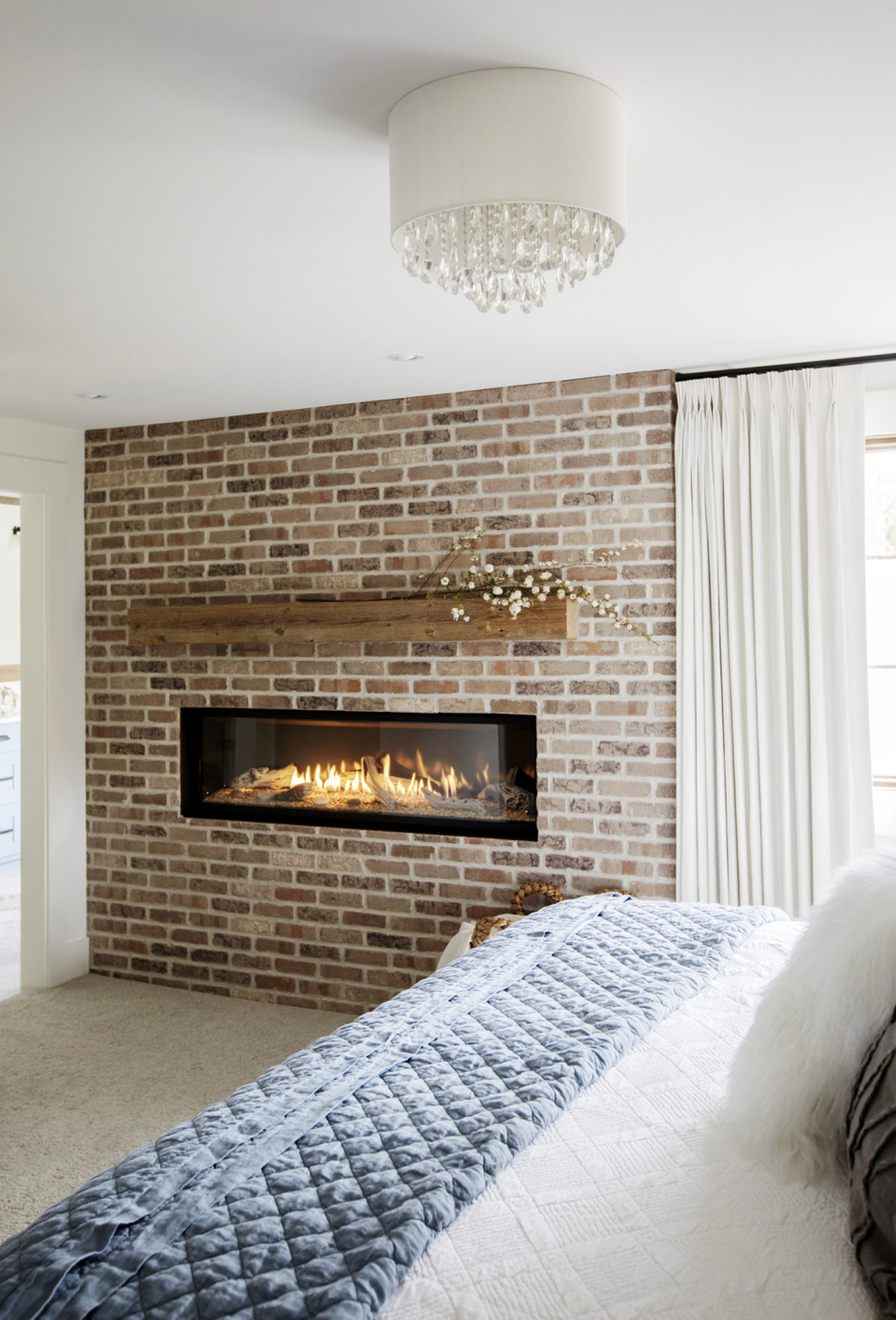 A bedroom with exposed brick wall and gas fireplace