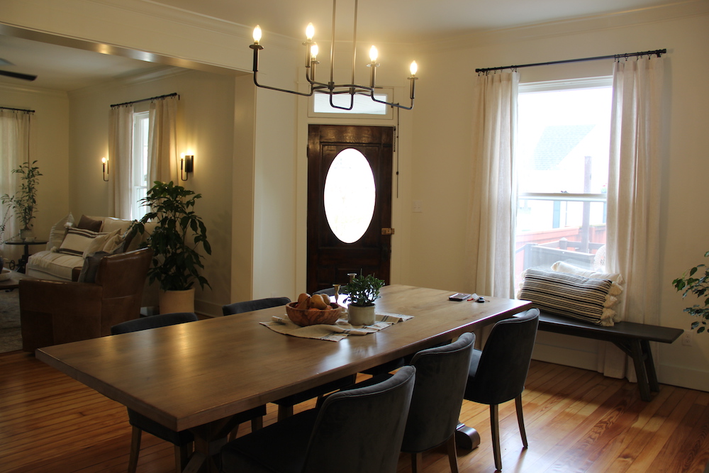 white dining room with hanging light fixture and wood table