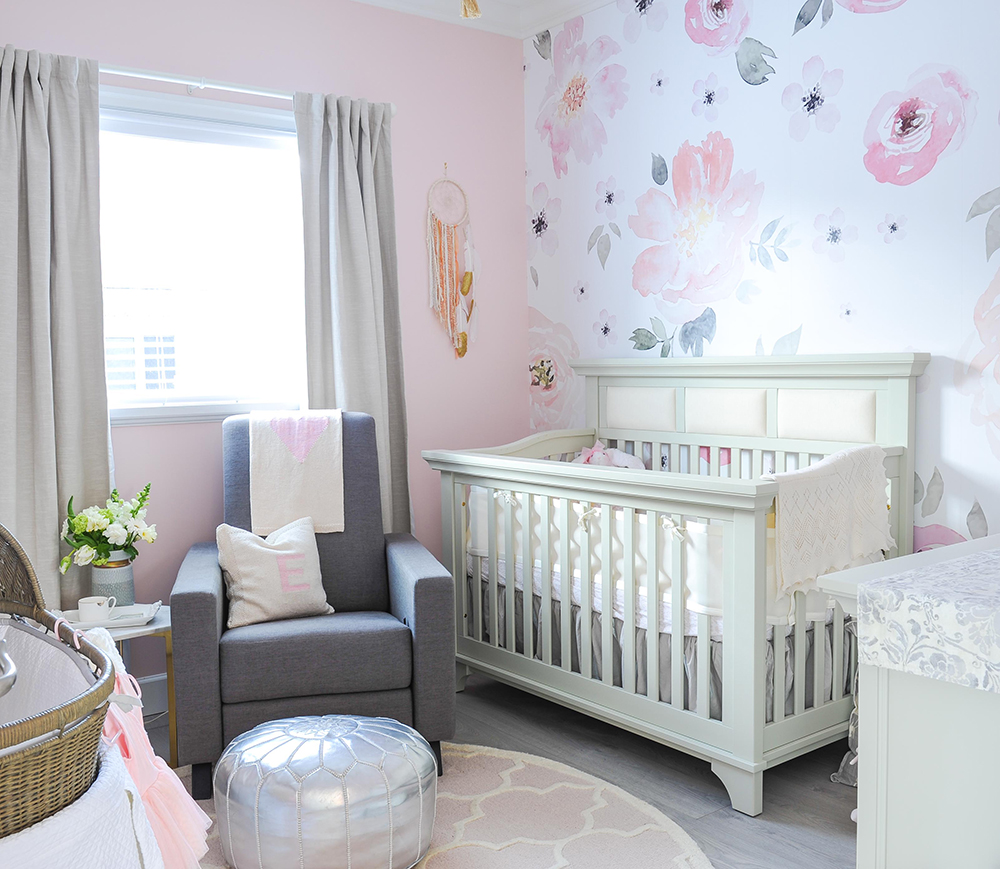 Feminine pink baby girl's room with floral wallpaper accent wall.