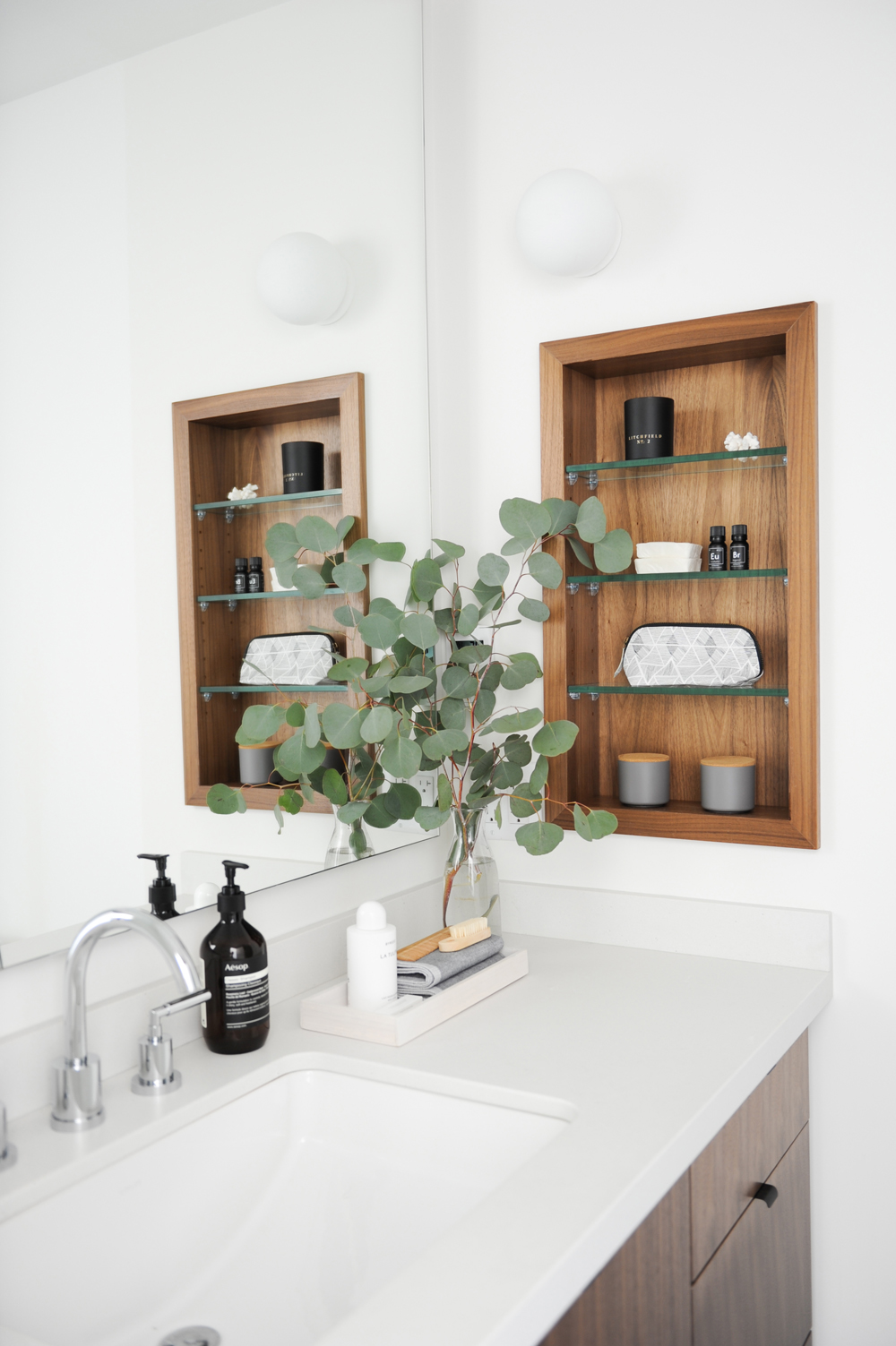 bathroom with walnut inset shelving and Aesop pump soap bottle beside tap