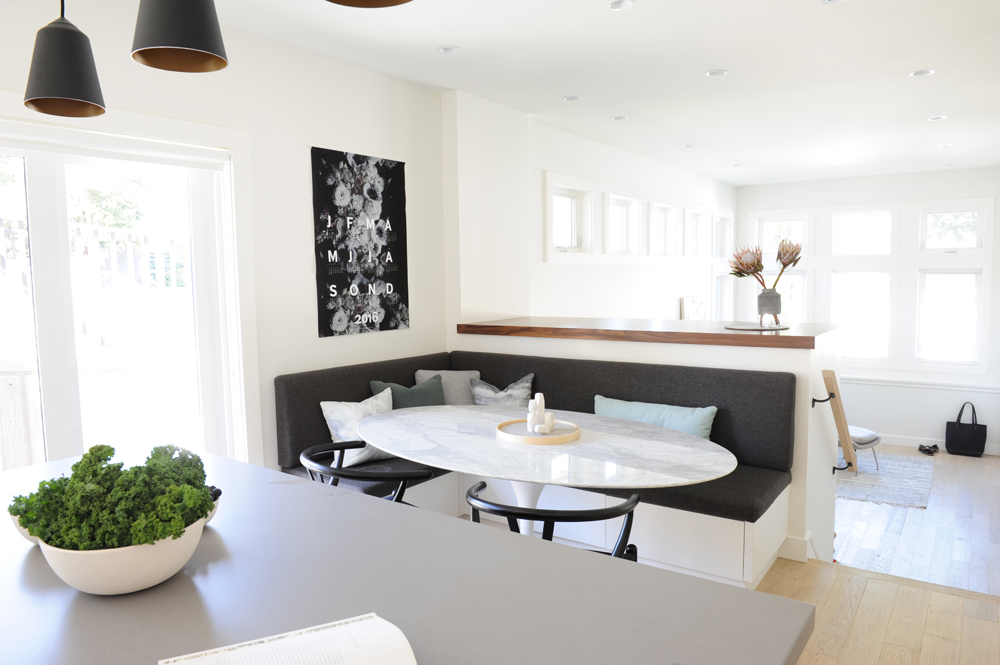 kitchen with grey banquette seating and bowl of lettuce on island