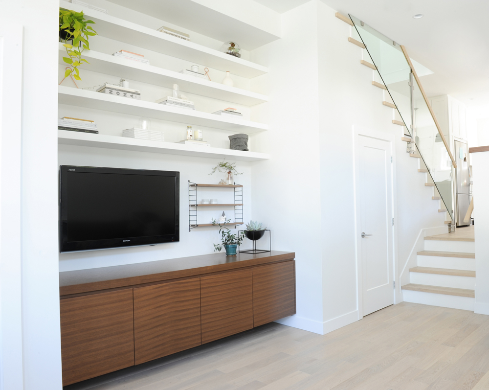 white floating shelves, TV, walnut credenza, view to four stairs and staircase