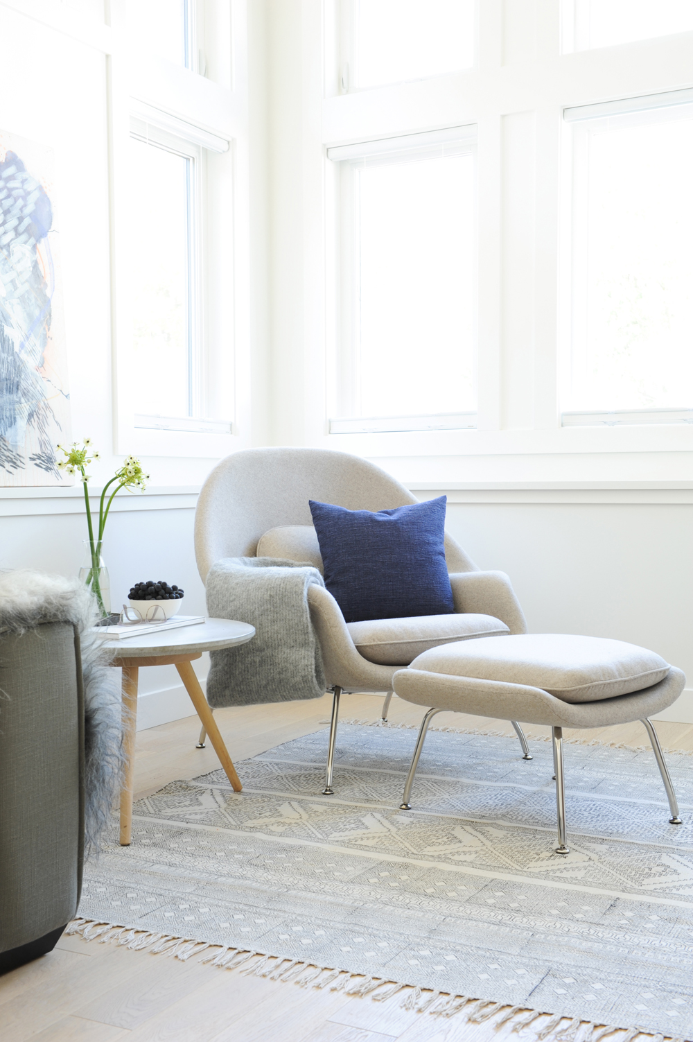 beige chair with matching stool, throw and blue cushion in windowed entry