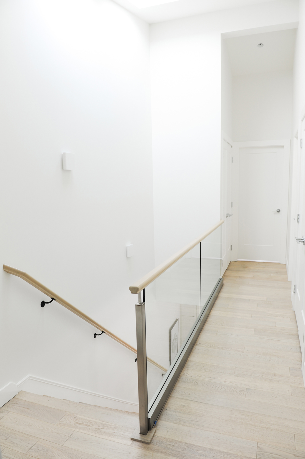 white upper hallway with glass panels, two white artwork on white wall