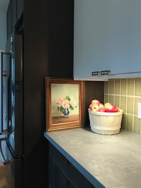 Leaning painting of flowers beside a fridge in a kitchen