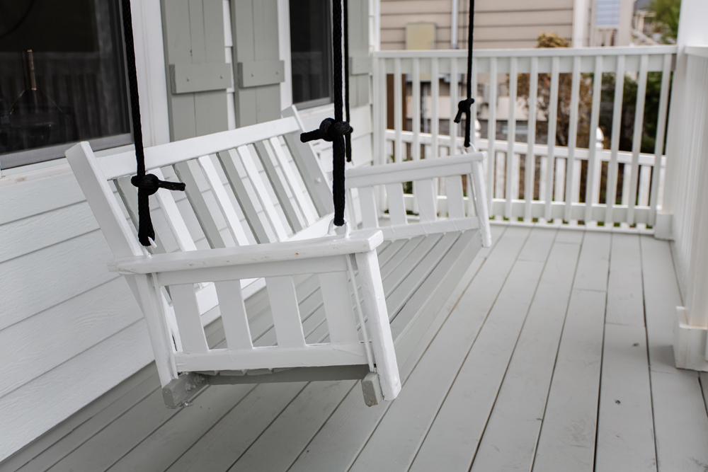 white porch swing on grey porch