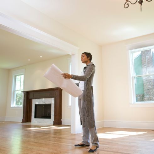 Person holding visual of floor layout and standing in new home.