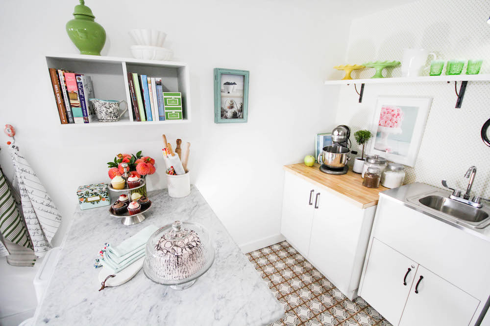 white interior of cake studio with marble counter, shelves and rolling sink