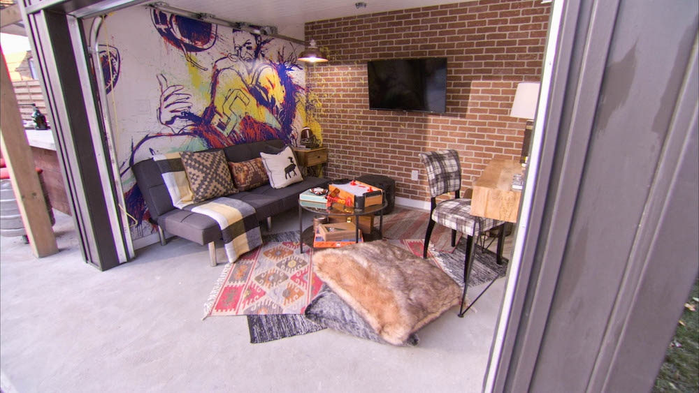 garage converted into lounge with faux-brick wall, sports mural and mounted television
