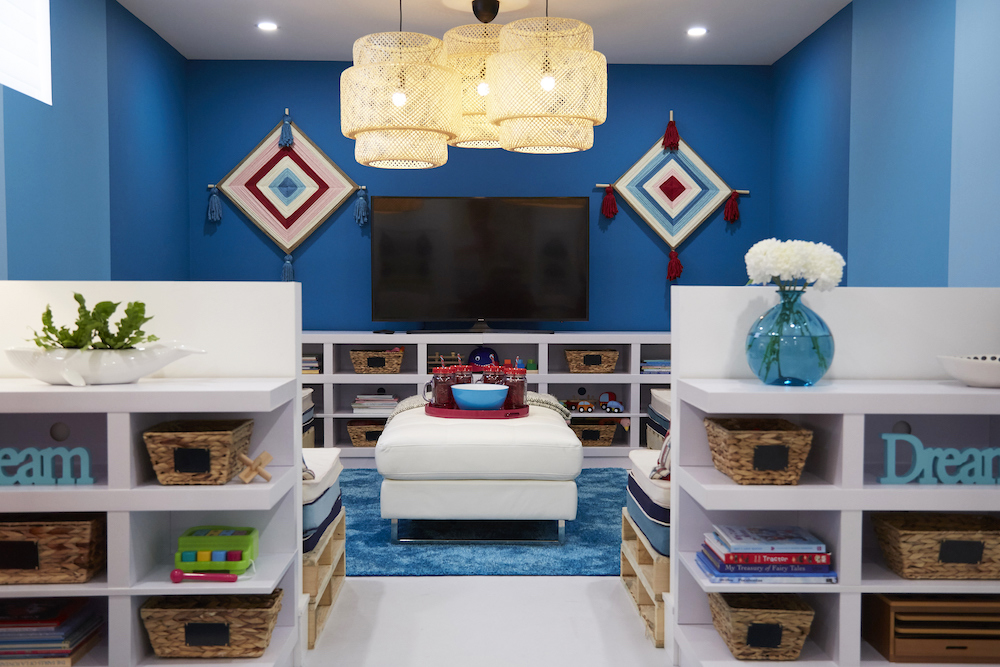 A vibrant blue playroom with plenty of storage space and unique lighting fixtures