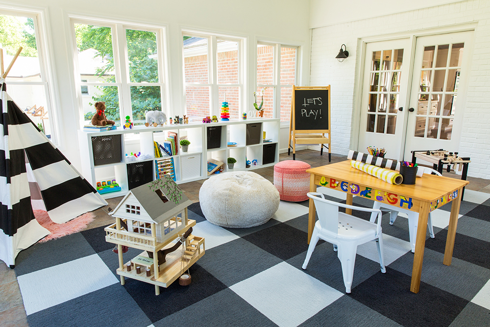 A black-and-white checkered playroom with lots of windows letting in natural light and French doors leading into the living room