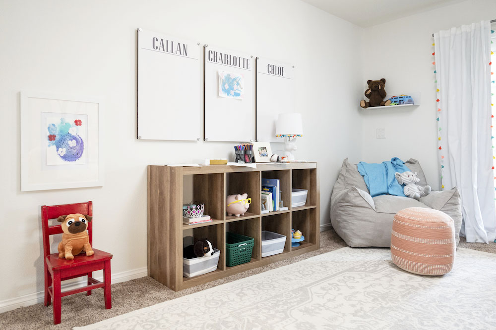 A minimalist kids playroom with storage space, beanbag chairs and picture boards for all three kids