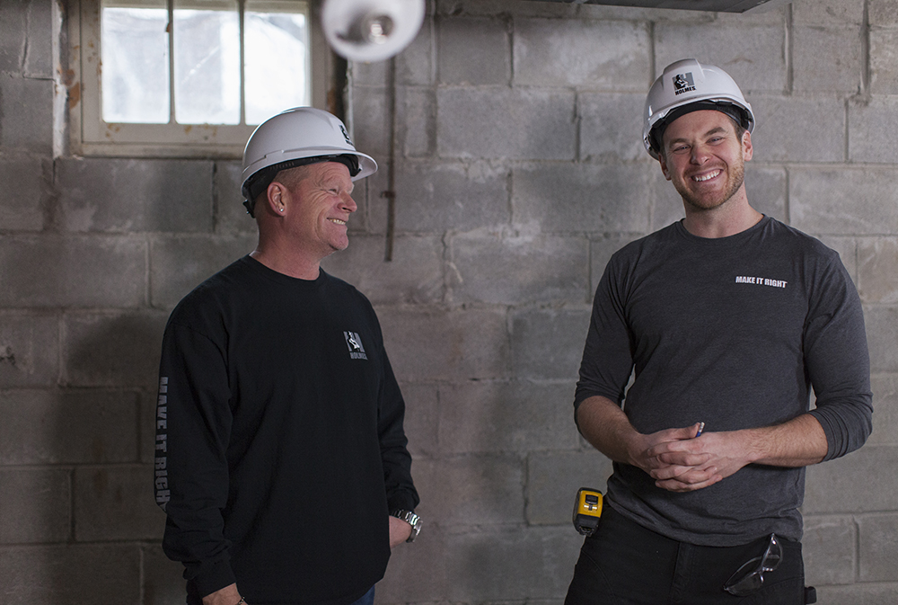 Mike Holmes and Mike Holmes Jr. in a basement
