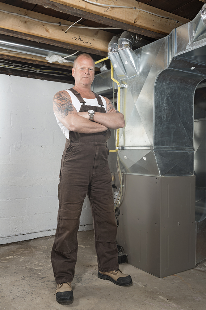 Mike Holmes standing beside a furnace
