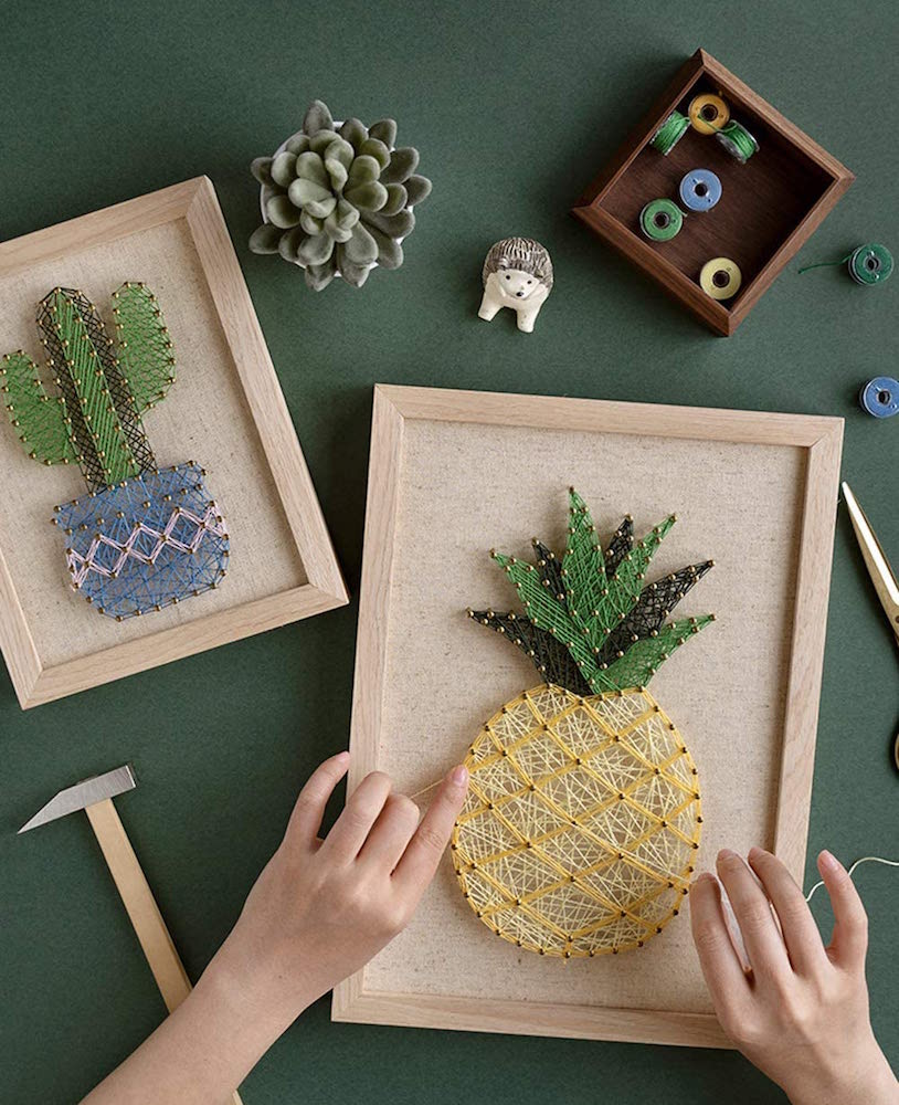 hands making a DIY string art pineapple