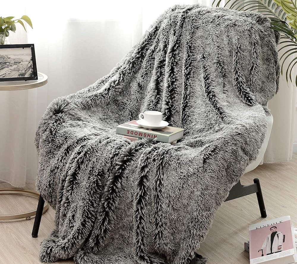 cozy living room with grey fuzzy blanket and books on chair