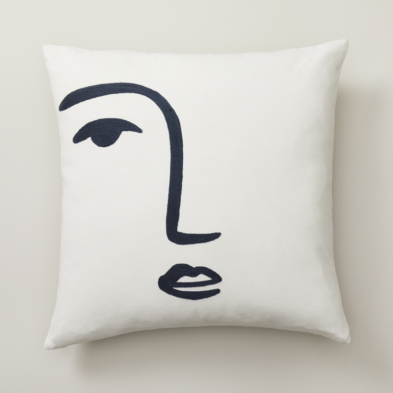 white pillow with navy brushstroke face design at front