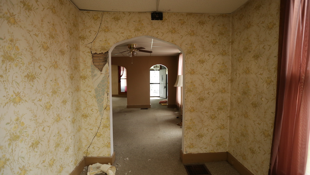 before wallway with damaged yellow floral wallpaper