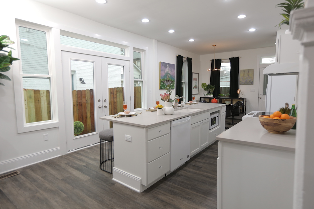 white kitchen with double French doors leading out to fenced outdoor space