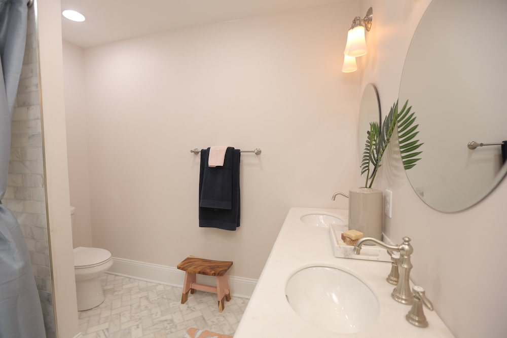 pink master bathroom with herringbone tiled floor and double vanity