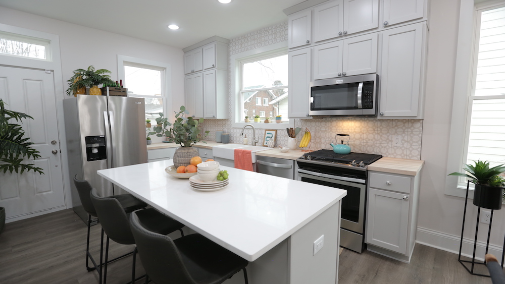 white open-concept kitchen with white centre island and black counter stools