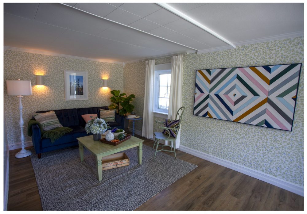 living room with green patterned wallpaper and blue couch