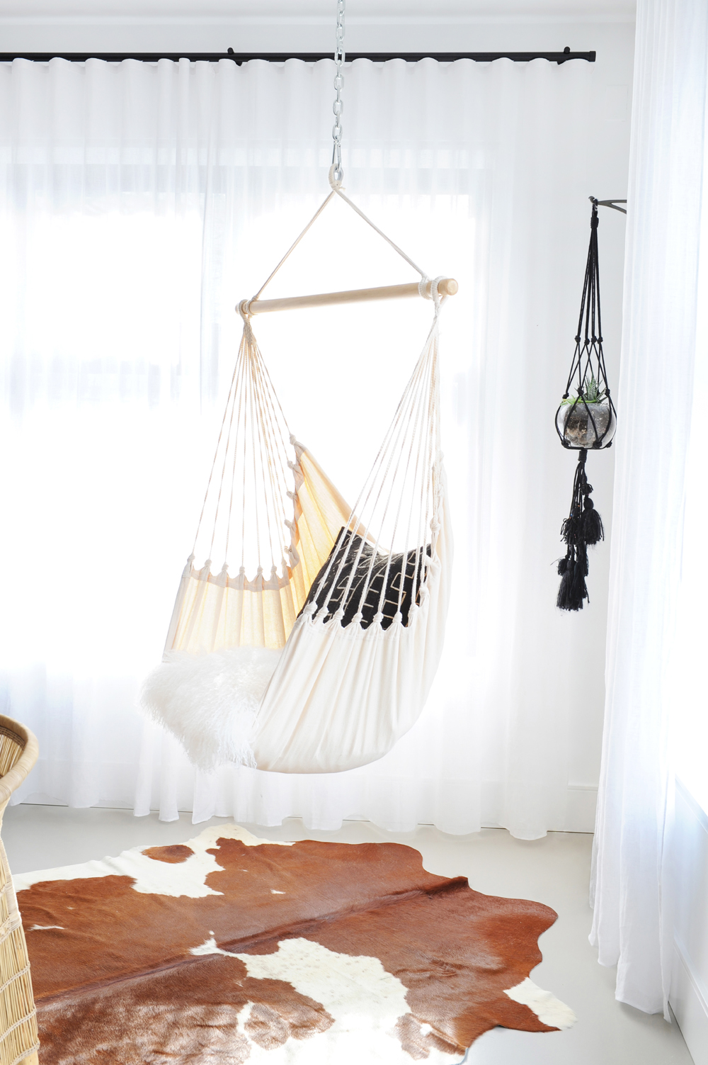 white hammock chair over tan and white ponyskin rug