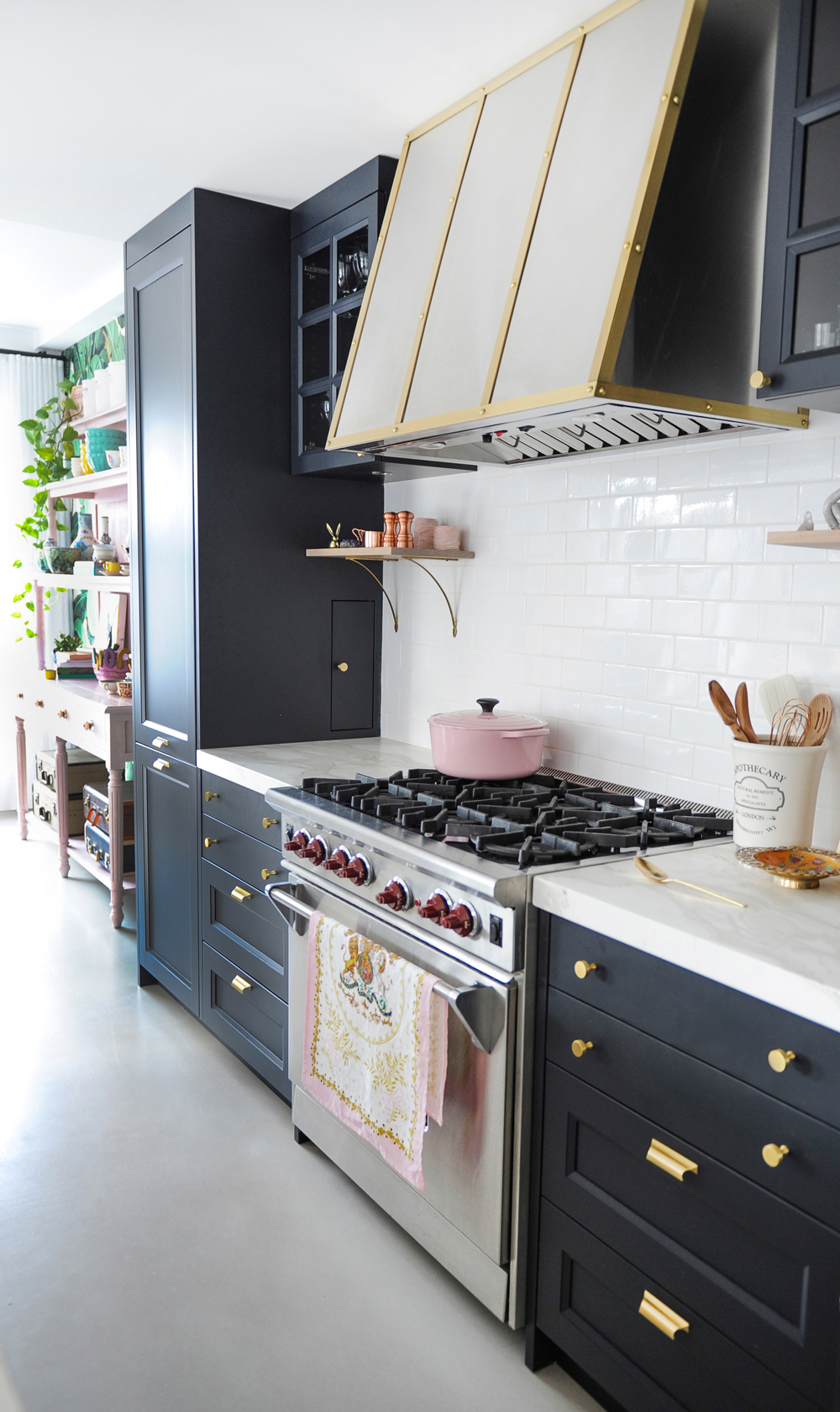 black and white kitchen with stainless steel, red knob oven with pink creuset pot on top