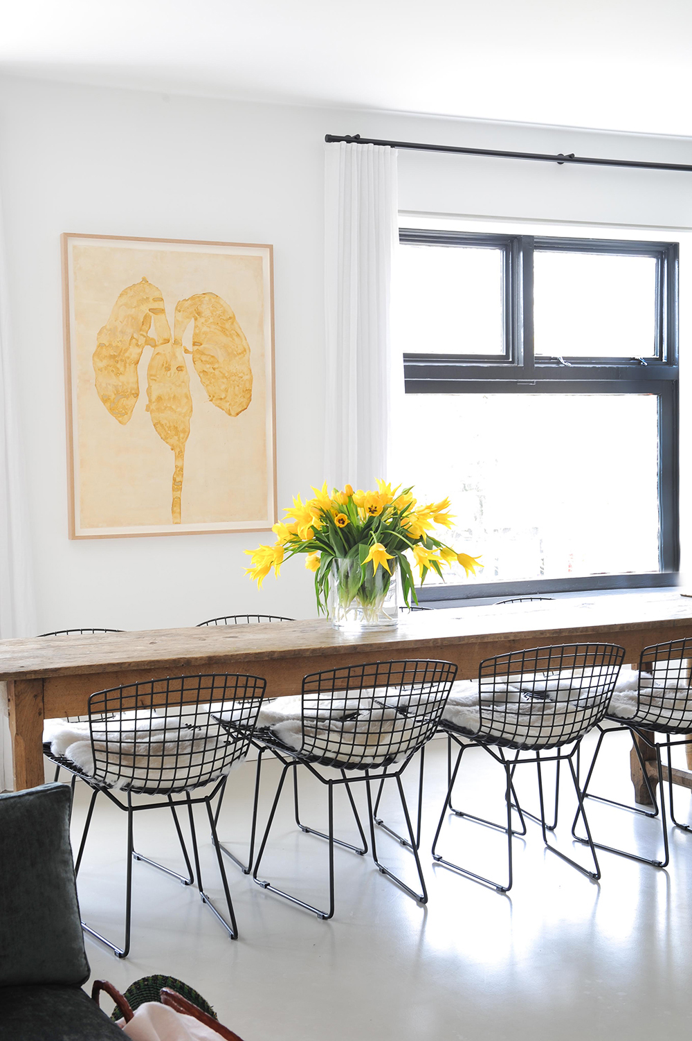 loft wooden long dining table with black wire chairs and yellow flower arrangement