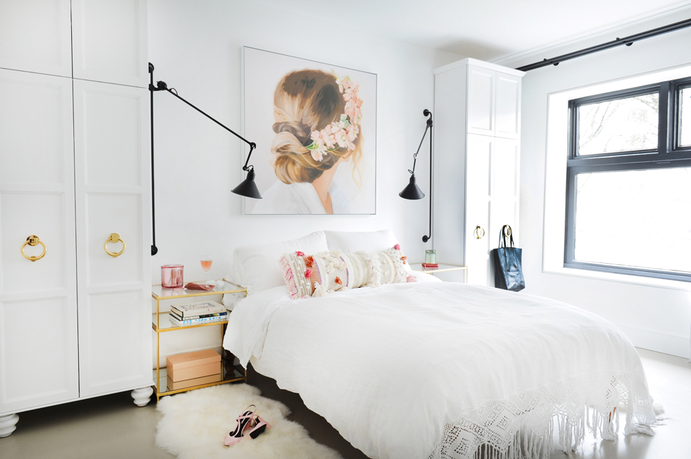 white bedroom with black sconces and art of back of woman's head with flowers in hair