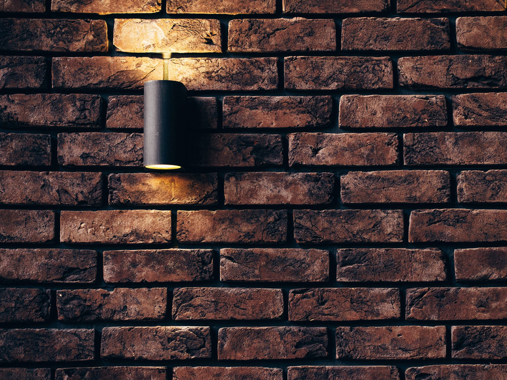 An exposed brick wall with a single light