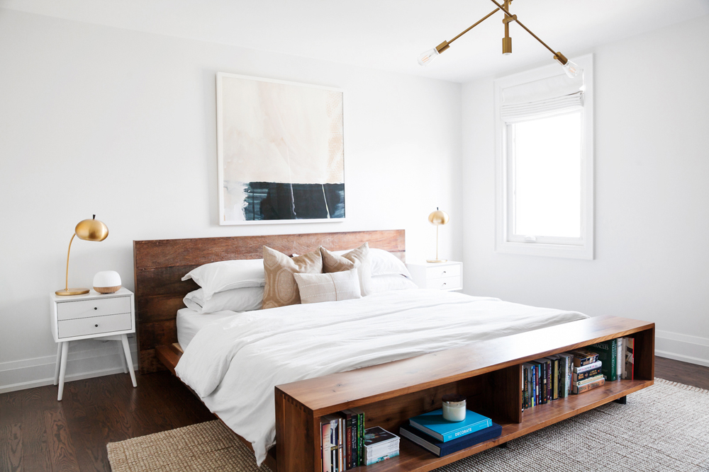 A clean master bedroom featuring a large bed with wooden headboards and open shelving at the end of the bed