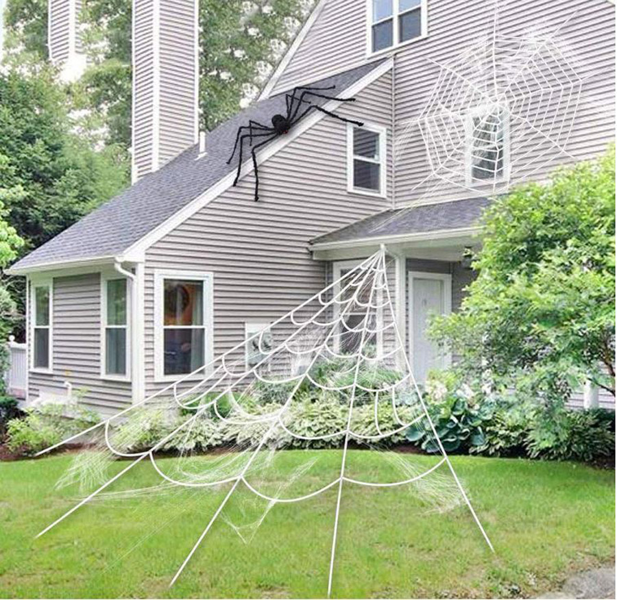 A house decorated with a stretchy oversized spider web with a fuzzy black spider on the roof