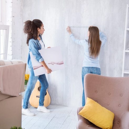 women measuring wall to hang picture