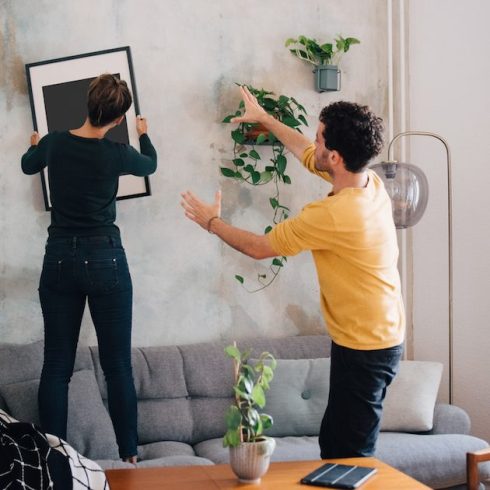 man guiding woman in hanging picture frame on wall