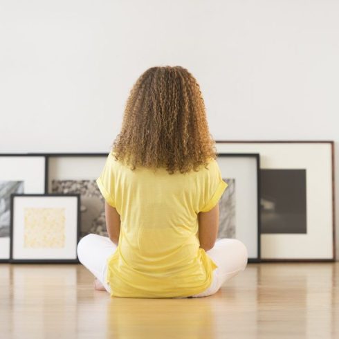 Woman sitting on floor looking at frames against white wall